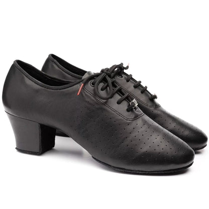 A pair of black leather dance shoes with low block heels, perforated detailing on the toe, and black laces, shown against a plain white background.