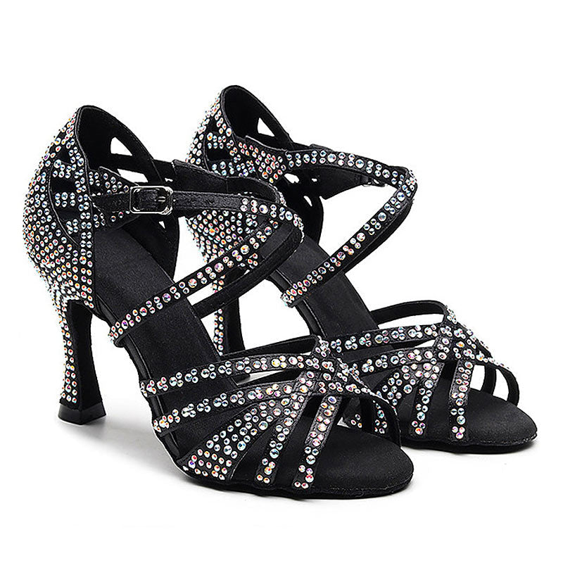 A pair of black strappy high-heeled dance shoes embellished with iridescent rhinestones, shown against a plain white background.